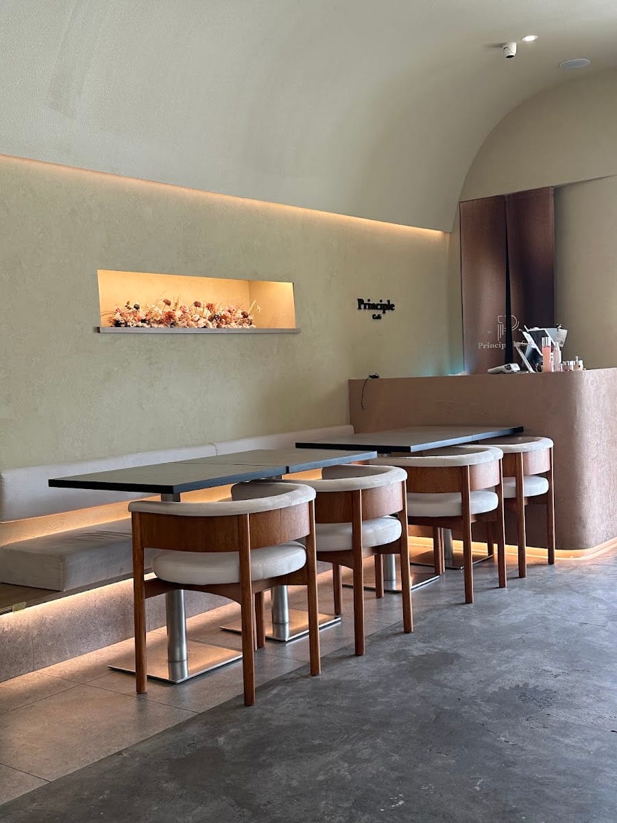 Banquette and wooden chairs under the Principle Café sign at Mount Austin