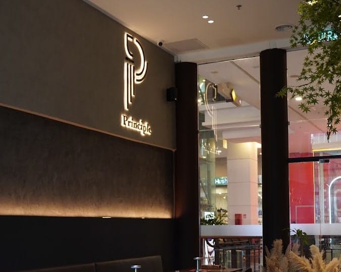 Principle Café Berjaya Times Square — the lit P Principle sign above the booth seating
