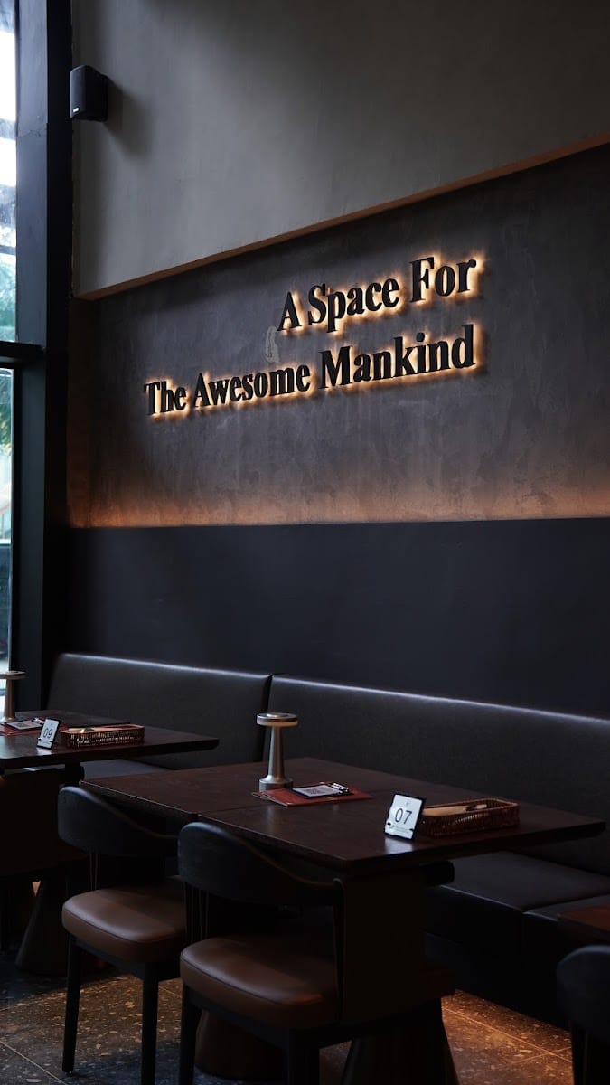 Lit sign reading A Space For The Awesome Mankind above booth seating at Berjaya Times Square